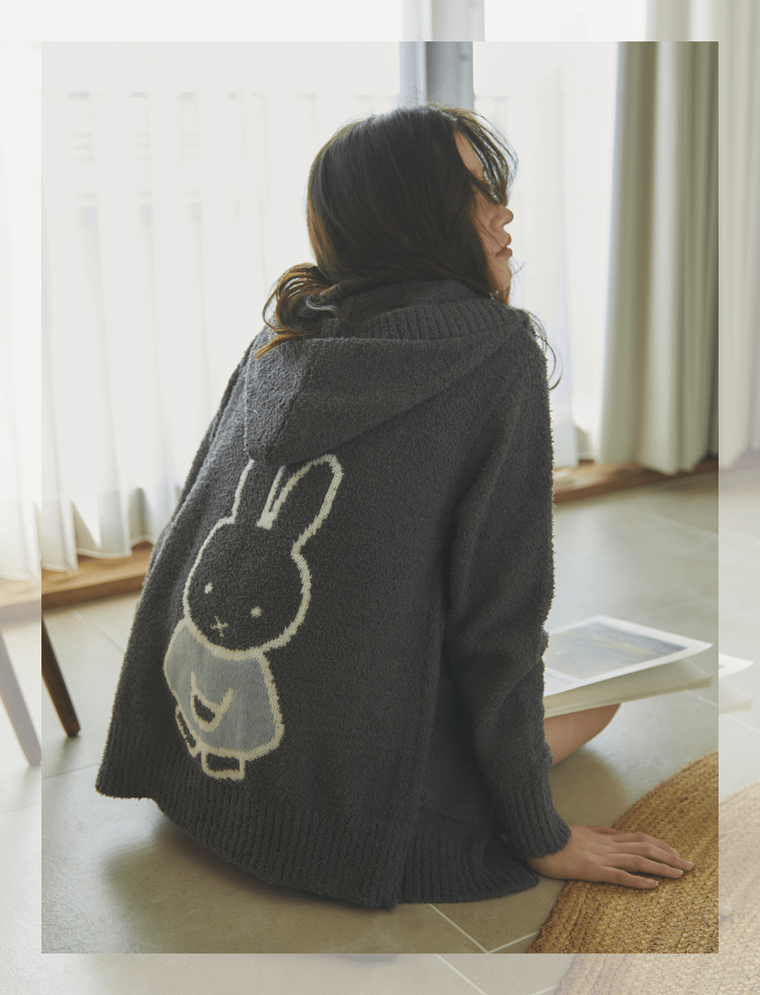 【ミッフィー/miffy】ミッフィー刺繍ニットパーカーと【ミッフィー/miffy】もこもこパンツを着用して床に座っている女性の後ろ姿の写真