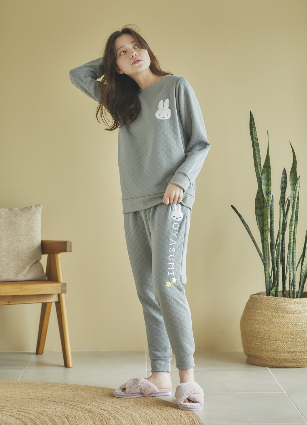 【【miffiy/ミッフィー】ミッフィー刺繍キルトプルオーバーと【miffiy/ミッフィー】ミッフィー刺繍キルトパンツを着用して斜め上を見る女性の写真