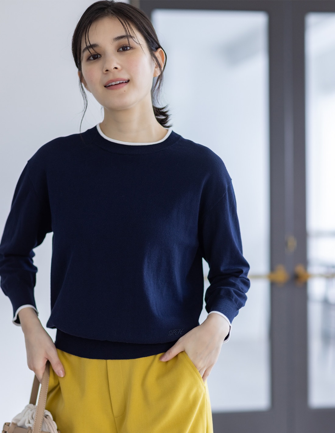 バイカラーニットプルオーバーとすご楽テーパードパンツを着用した女性１