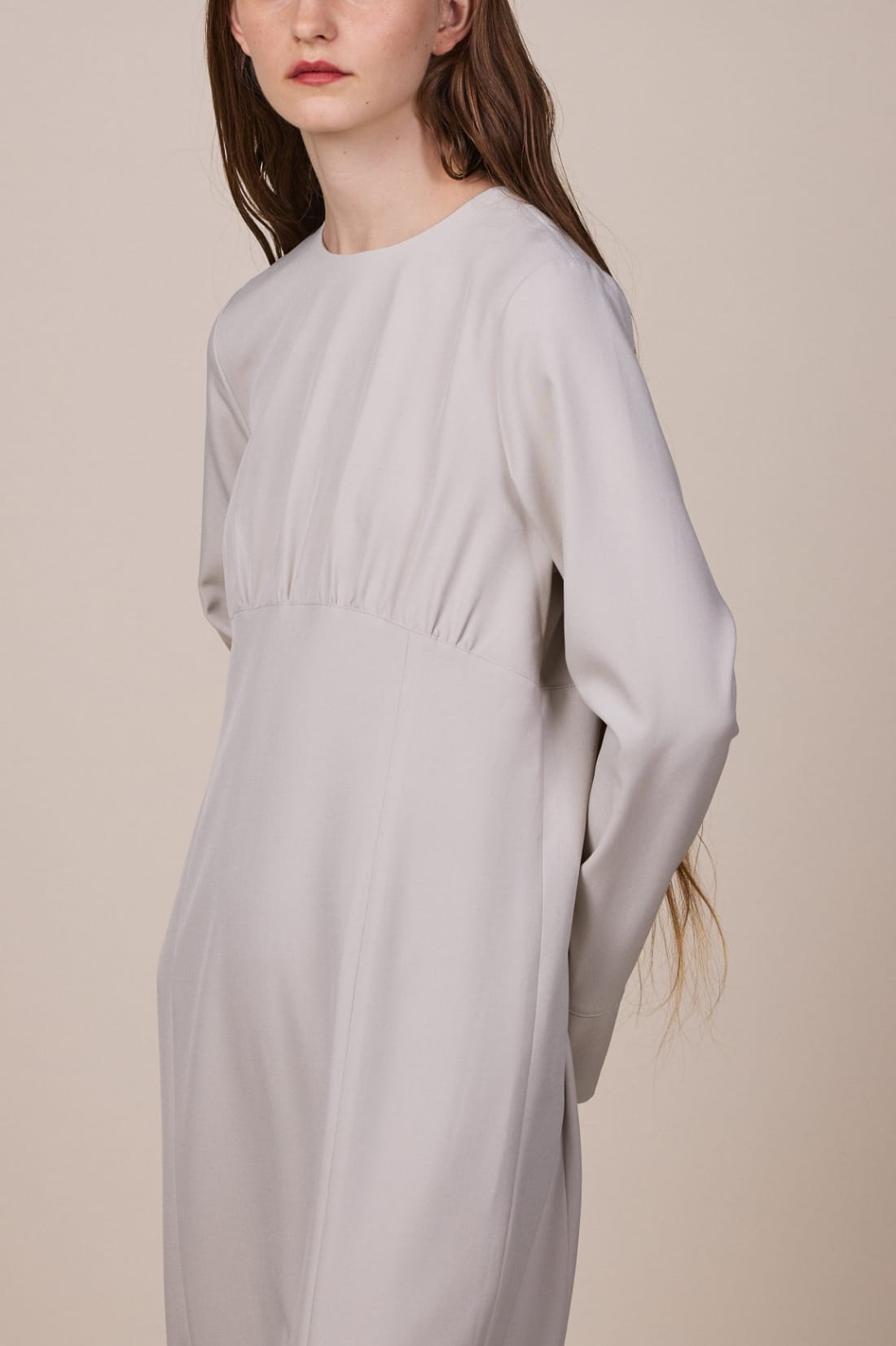 ウエストギャザーセミタイトワンピースを着用している女性モデルの、腰から上の写真 sp