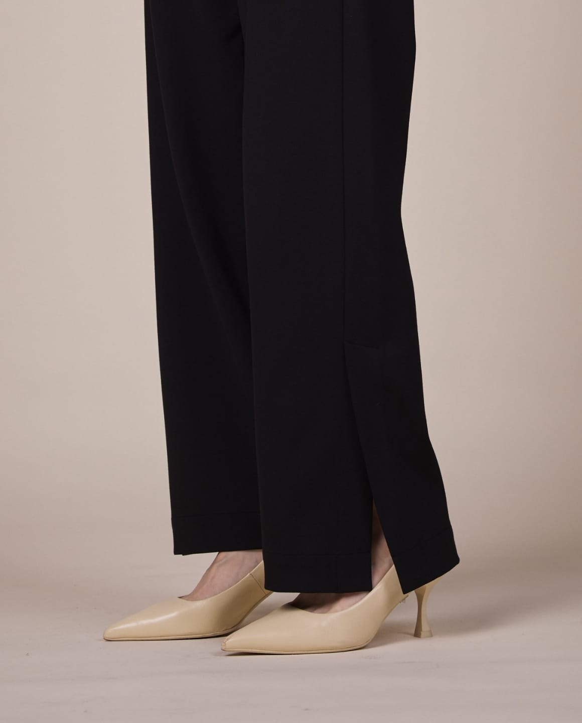 ノーカラージレブラック、スリットパンツブラックを着用している女性モデルの足元写真