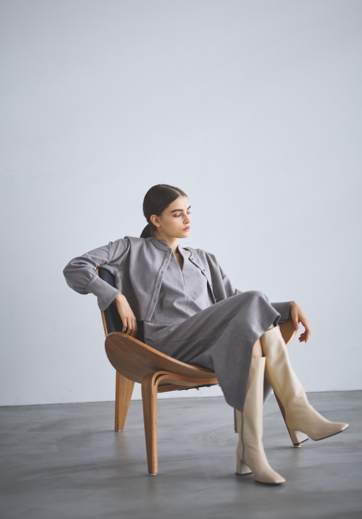 ショートカーデ＆ジャンスカSETワンピースを着用して椅子に腰掛けた女性の全身の写真