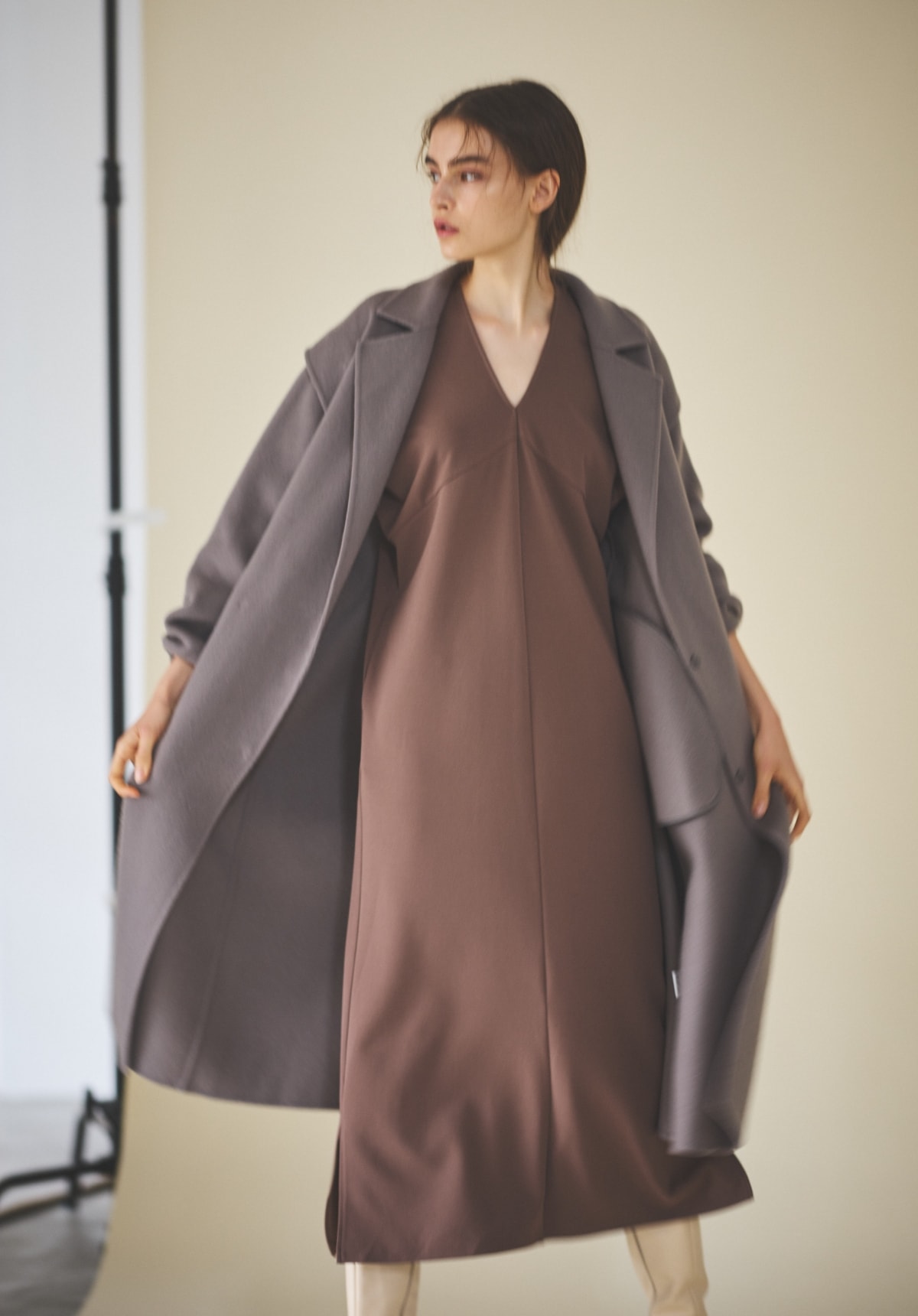 ドルマンスリーブカットジャカードワンピースを着用した女性がコートを羽織っている写真