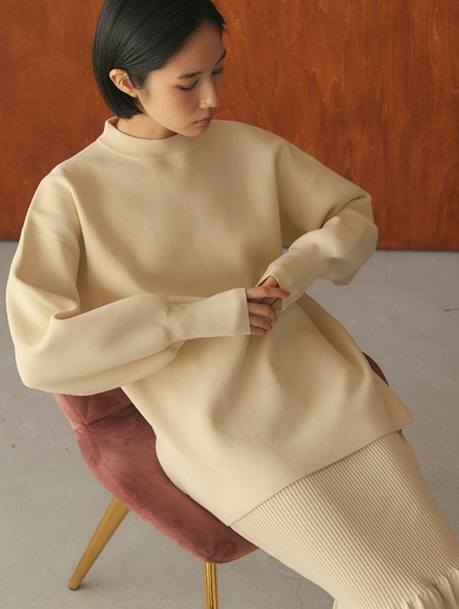 Yuki Ideコラボアイテムセットアップニットを着用した女性が椅子に腰掛けている写真