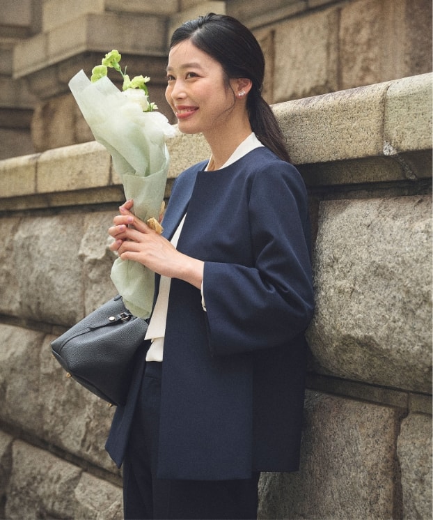 《洗える・シワになりにくい》正解Aラインフレアジャケットと《洗える・シワになりにくい》正解テーパードパンツと《シワになりにくい》シルキーサテンパールボウタイブラウスを着用している女性３