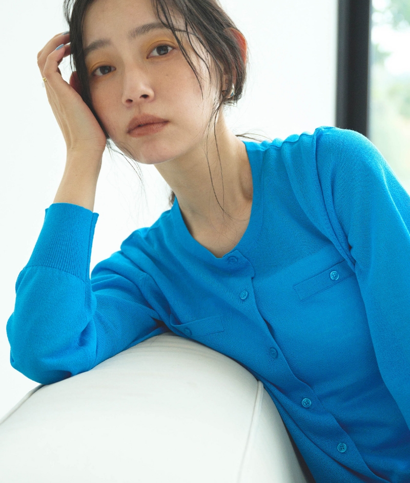 ターコイズブルーの《洗える》サマ美え フロントポケットシアーカーディガン・ネイビーの《UV/吸水速乾》エブ楽 きれいめイージーパンツを着用した女性のアップの画像