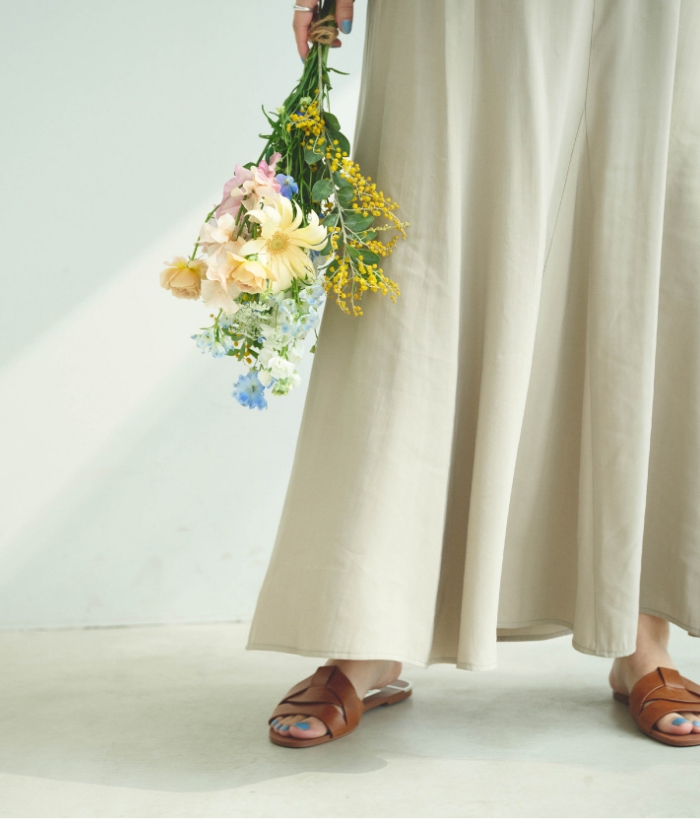 ベージュの《接触冷感》サマ美えとろみワークディテールドレープシャツ・ベージュの《接触冷感》サマ美えとろみフレアマーメードスカートを着用した女性の手元の画像