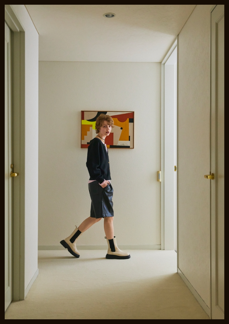 こちらを見ながら絵画の前の廊下を歩く女性