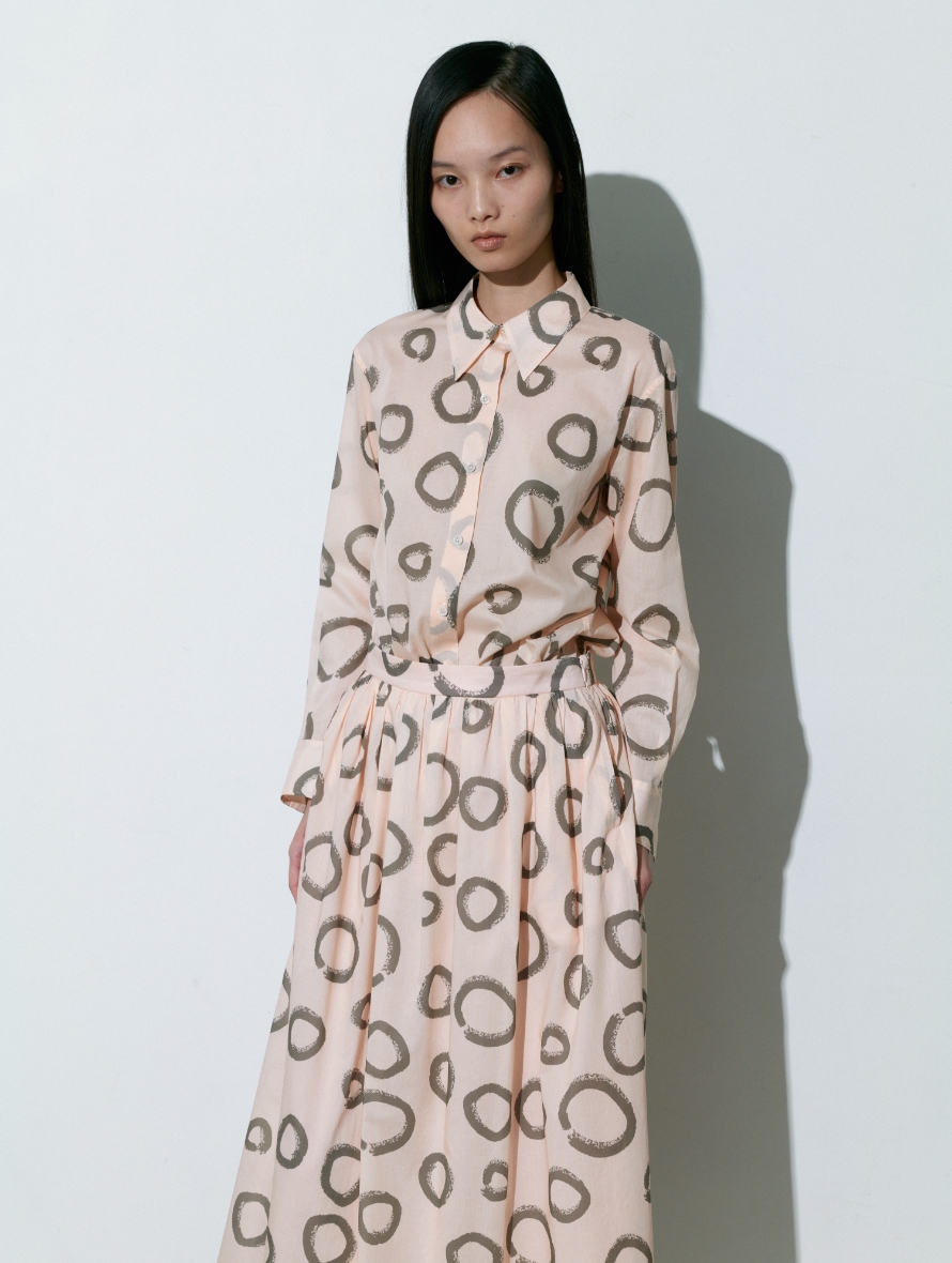 丸い模様のBlouse、Skirtを着用している女性の画像