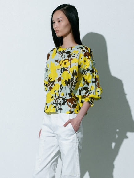 金色とミント色が混ざった柄のBlouseと白色のPantsを着用している女性の画像