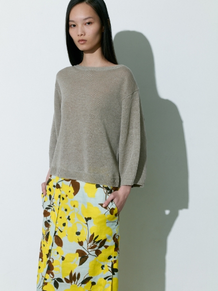 燻んだベージュ色のPulloverと金色とミント色が混ざった柄のSkirtを着用している女性の画像