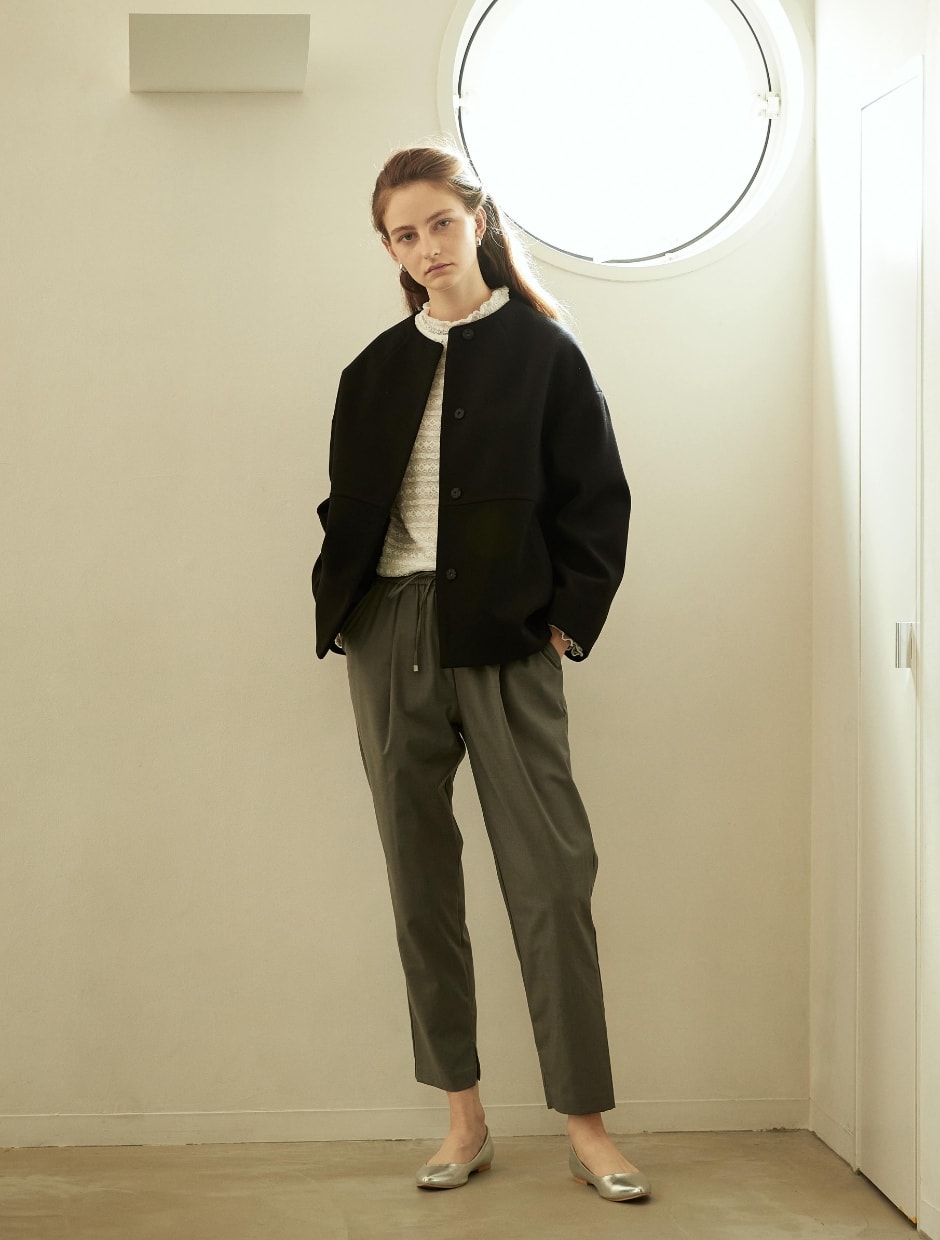 コートとプルオーバーとパンツとネックレスを着用した女性の写真