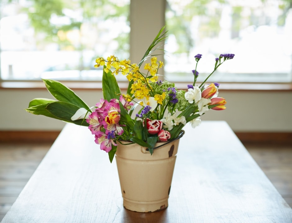 色とりどりの花が花瓶に入れられ、テーブルの上に飾られている写真