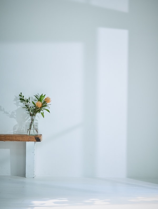 椅子に花瓶が飾ってある白い部屋の写真