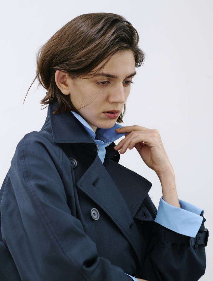 ネイビー色のロングトレンチコートとコンフォータブルシャツを着用した女性の画像