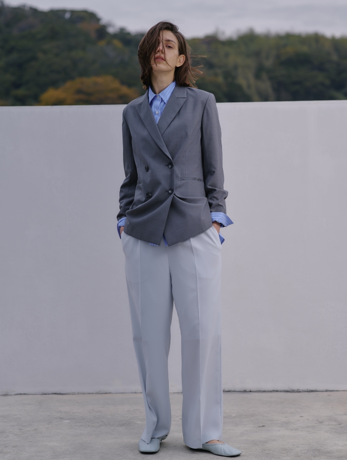 ピークドラペルダブルジャケット【CLEAN MOTION】とネイビーストライプのコンフォータブルシャツ、バックサテンストレッチタックストレートパンツを着用した女性の画像