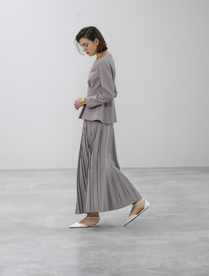 グレージュ色のウォッシャブルペプラムブラウス【CLEAN MOTION】とプリーツスカート【CLEAN MOTION】を着用した女性の画像02