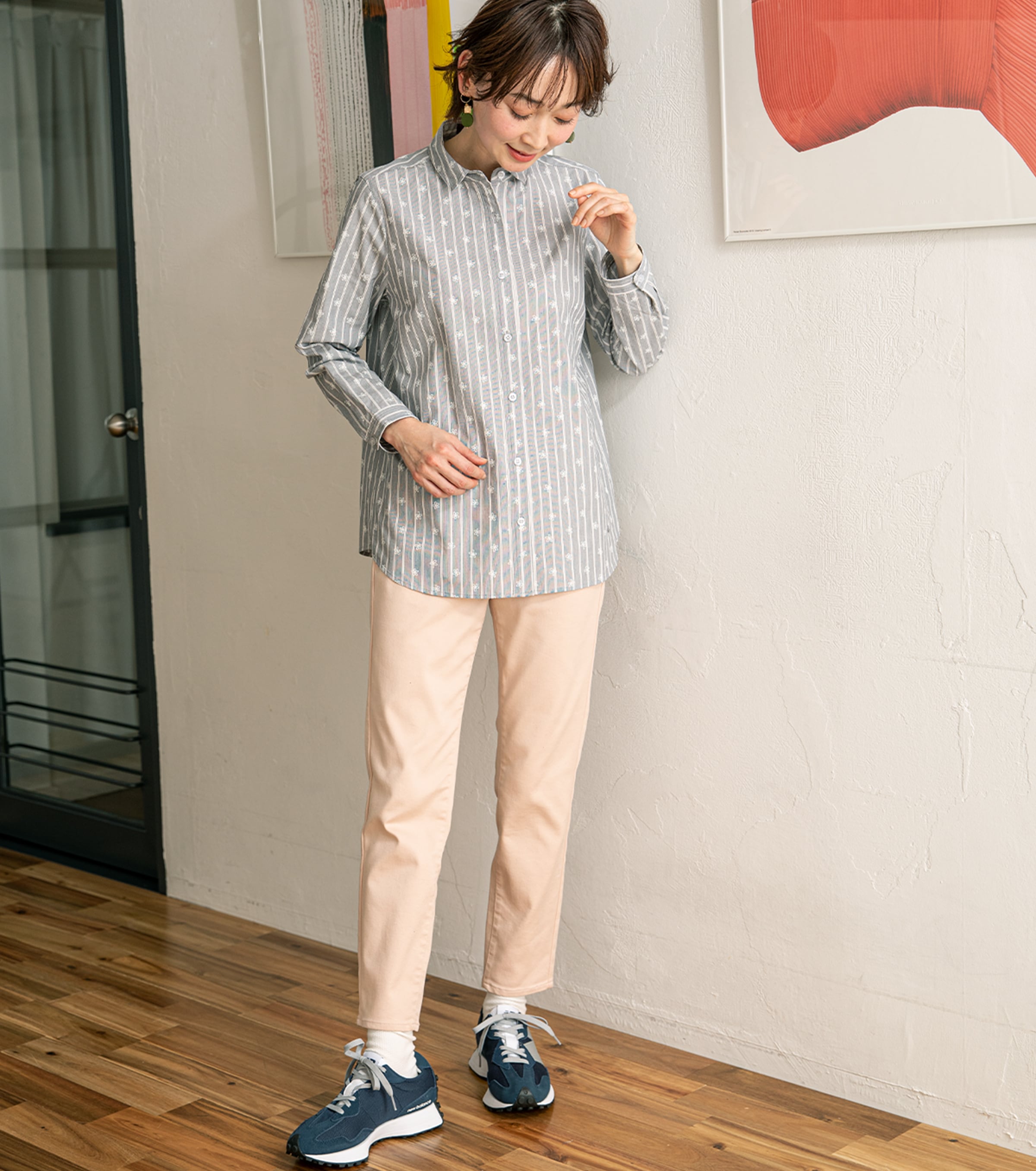 シャツとパンツの爽快コーデを花柄で柔らかく ストライププリントシャツ・グレーを着用している女性の写真